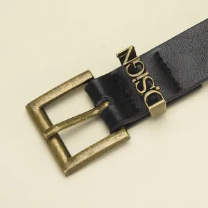 Primer plano de un cinturón de cuero negro con hebilla de bronce antiguo y presilla metálica.