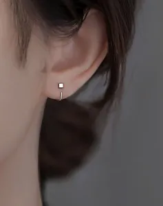Gedetailleerde close-up van minimalistische geometrische zilveren vierkante oorbellen