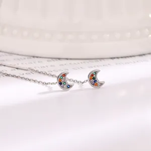 Macro detail of silver crescent moon threader earrings featuring colorful pavé cubic zirconia