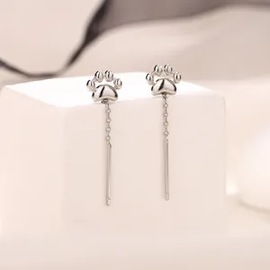 Gros plan de boucles d'oreilles pendantes pattes de chat en argent, bijoux mignons