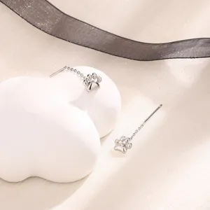Détail de boucles d'oreilles en forme de patte de chat argentées sur un support décoratif