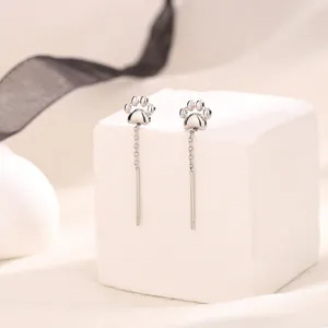 Vue détaillée de boucles d'oreilles en fil de patte de chat argentées sur socle blanc