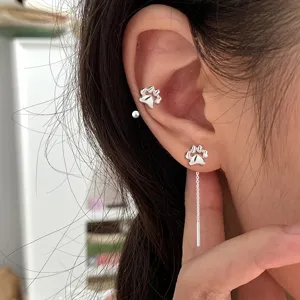 Vue détaillée de boucles d'oreilles patte de chat en argent sur l'oreille d'un modèle