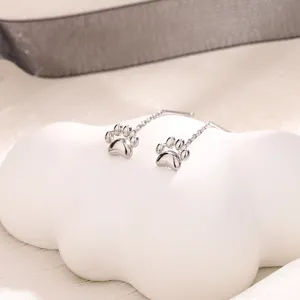 Boucles d'oreilles pendantes patte de chat en argent sur support blanc.
