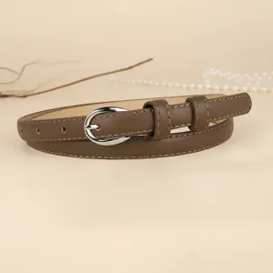 Close-up of elegant brown thin leather belt with silver oval buckle and stitching