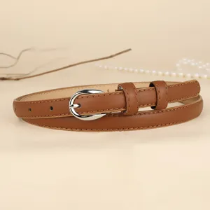 Elegant close-up of a minimalist brown slim leather belt with a silver horseshoe buckle.