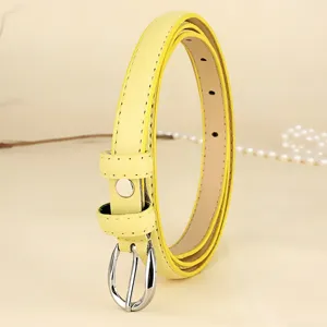 Macro detail view of a vibrant yellow skinny leather belt featuring a sleek silver buckle