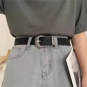 Vintage women's black faux leather belt featuring an ornate silver carved buckle on grey denim