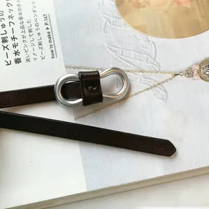 Detail view of women's slim dark brown leather belt with a silver infinity buckle.
