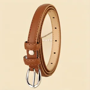 Detailed macro view of a minimalist slim brown leather belt with silver buckle