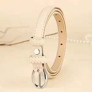 Close-up macro view of a minimalist beige thin leather belt for women with silver buckle detail