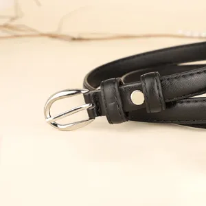 Close-up detail of a minimalist black narrow leather belt with a silver oval buckle.