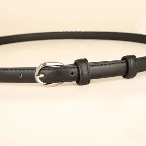 Close-up detail of a minimalist women's black thin leather belt with a silver oval buckle