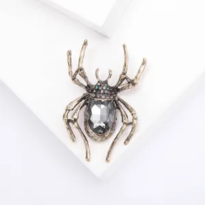 Vintage alloy spider brooch with faceted grey crystal and green rhinestone eyes