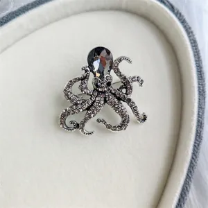 Detaillierte Nahaufnahme einer silbernen Oktopus-Brosche mit grauen Strasssteinen.