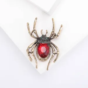 Detailed macro view of vintage spider brooch with red rhinestone and antique gold.