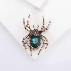 Exquisite close-up of a vintage gold spider brooch featuring a large emerald green gemstone