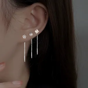 Detailopname van zilveren geometrische CZ kwastjes oorbellen en minimalistische knopjes