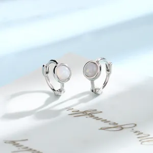 Close-up detail of minimalist silver hoop earrings with round white opal stone.