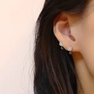 Detailed close-up view of minimalist round opal ear cuffs worn on a person's earlobe
