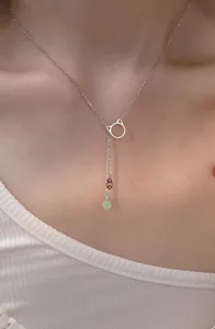 Dettaglio di una collana a tema gatto minimalista con giada Hetian e nappa moneta