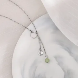 Dettaglio della collana gatto in argento con perla di giada verde e ciondoli a moneta.
