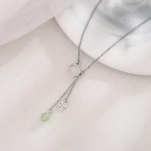 Vista dettagliata di una collana a gatto in argento con perla di giada verde e ciondolo a moneta