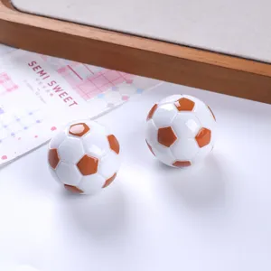 Dettaglio macro di ciondoli a forma di pallone da calcio 3D in resina per gioielli fai da te