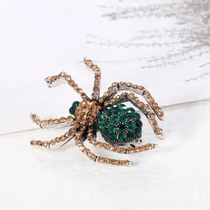 Nahaufnahme einer Vintage-Spinnenbrosche mit grünen und goldenen Strass