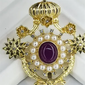 Vista dettagliata della spilla a corona barocca dorata con perle e gemma viola