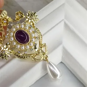Dettaglio di una spilla barocca con pietra viola e perla a forma di goccia.