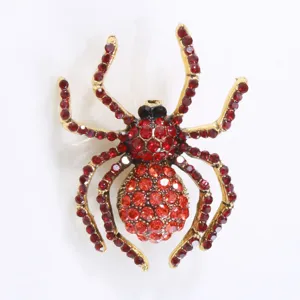 Makrodetail einer Vintage-Goldspinne-Brosche mit roten und orangefarbenen Strasssteinen.