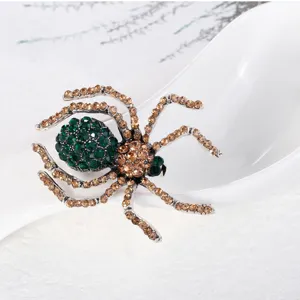 Makroaufnahme einer Vintage-Spinnenbrosche mit grünen und goldenen Strasssteinen