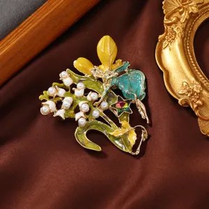 Close-up of enamel lily-of-the-valley brooch with pearls and fairy detail