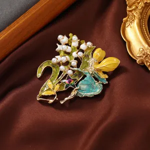 Detailed macro shot of an elegant enamel fairy brooch featuring pearls and crystals