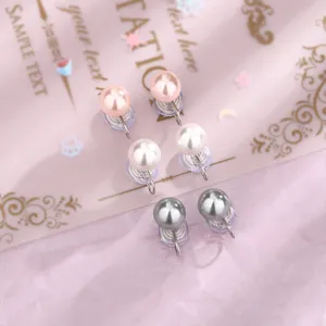 Primo piano di tre paia di eleganti orecchini a clip con perle rosa bianche e grigie