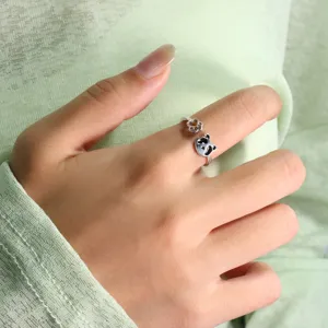 Close-up detail of a cute silver panda open ring featuring a paw print on a index finger