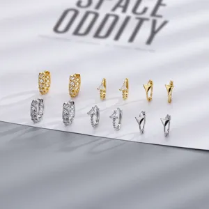 Primo piano di vari orecchini a cerchio geometrici in zircone color oro e argento.