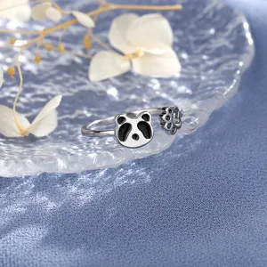 Close-up of cute silver panda ring with paw print on textured glass background