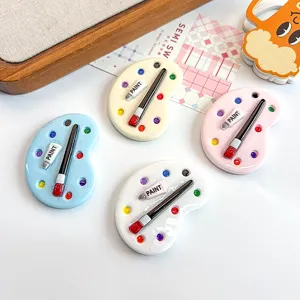 Detail shot of miniature resin artist palette charms in four soft pastel colors