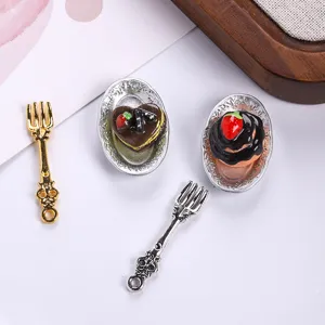 Close-up view of detailed miniature dessert plates and vintage forks for DIY dollhouse