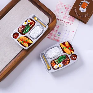 Close-up of miniature silver bento box refrigerator magnets with realistic food details