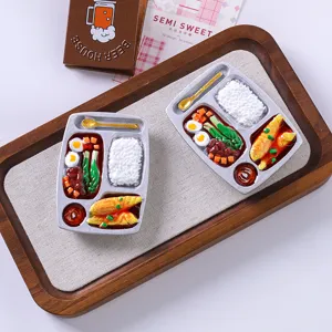 Detailed macro view of two realistic resin bento box magnets on a wooden tray