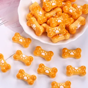 Close-up of orange bone-shaped resin charms with white paw print for DIY crafts