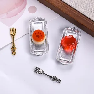 Close-up detail of miniature resin food on ornate silver trays with tiny forks for dollhouse