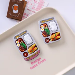 Close-up of realistic bento box resin fridge magnets on a decorative tray.