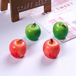 Detailed macro view of realistic miniature resin apples in glossy red and green colors