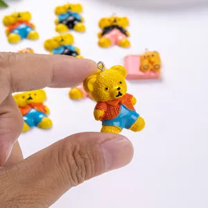 Detailed macro view of a cute yellow resin teddy bear charm for DIY jewelry and crafts