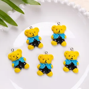Macro view of five cute yellow teddy bear resin charms on a textured white plate.