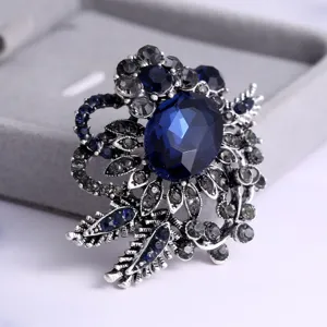 Close-up detail of a dark blue medieval retro flower brooch with faceted gemstone